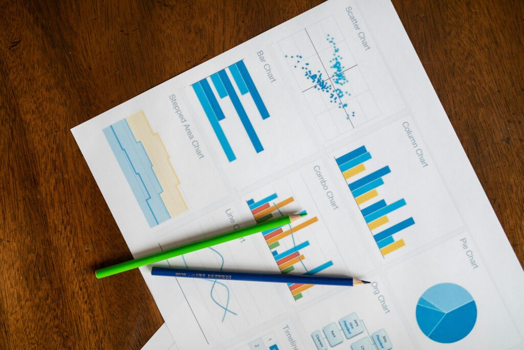 Top view of vibrant charts and colored pencils on wooden surface.